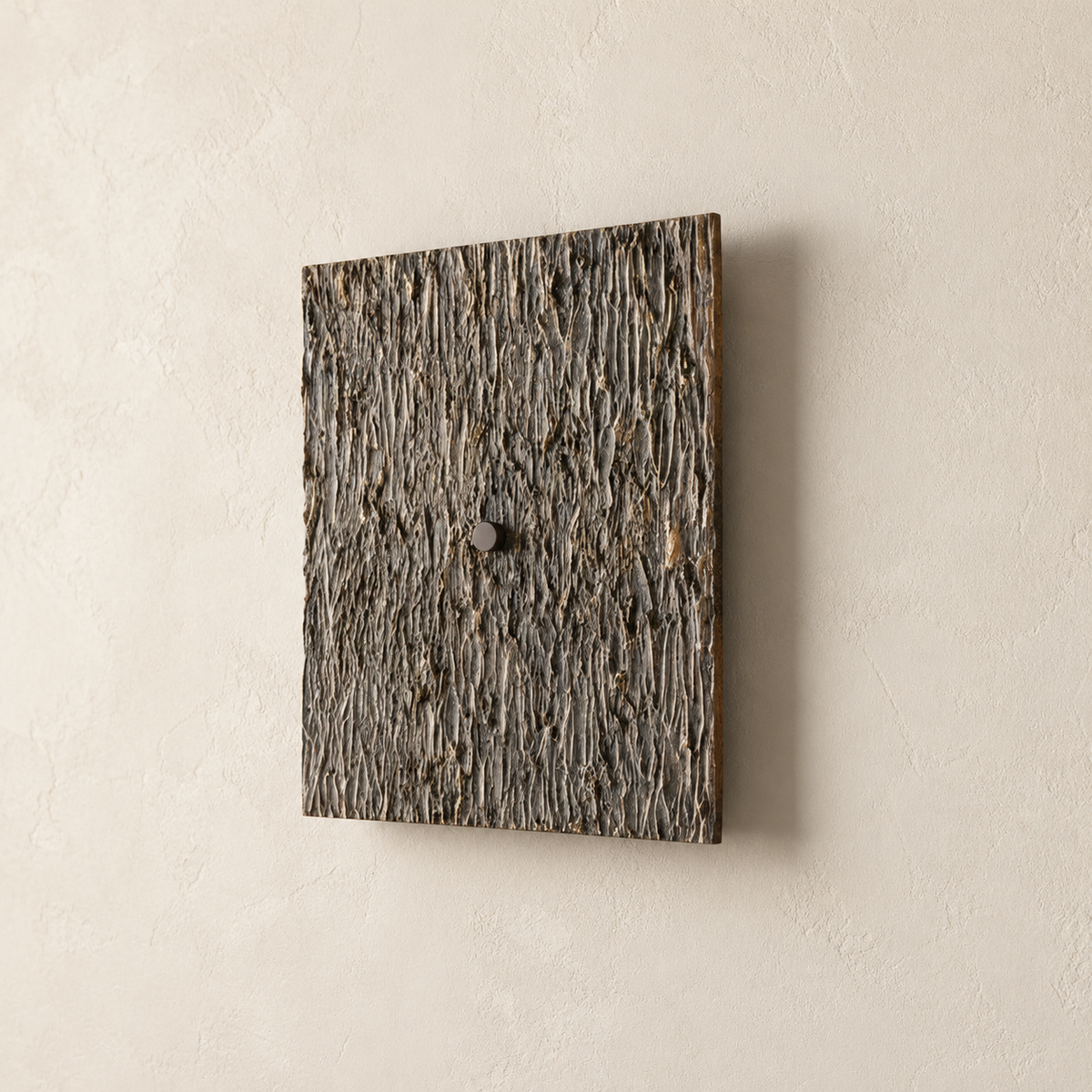 Angled view of the dark Ratera relief wall sconce showing its textured face and shallow profile.