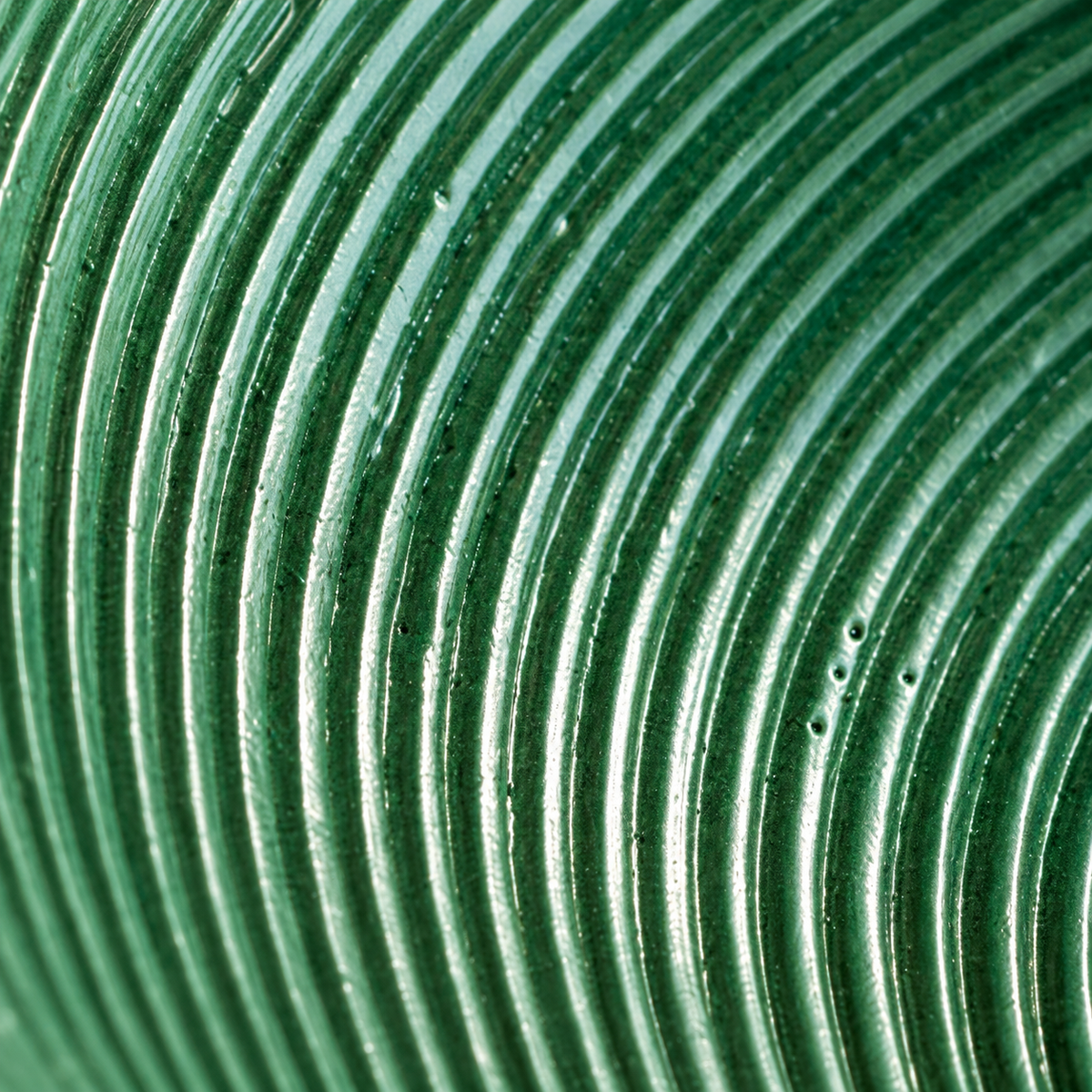 Close-up of the green ceramic lamp’s concentric ridges and glazed surface.