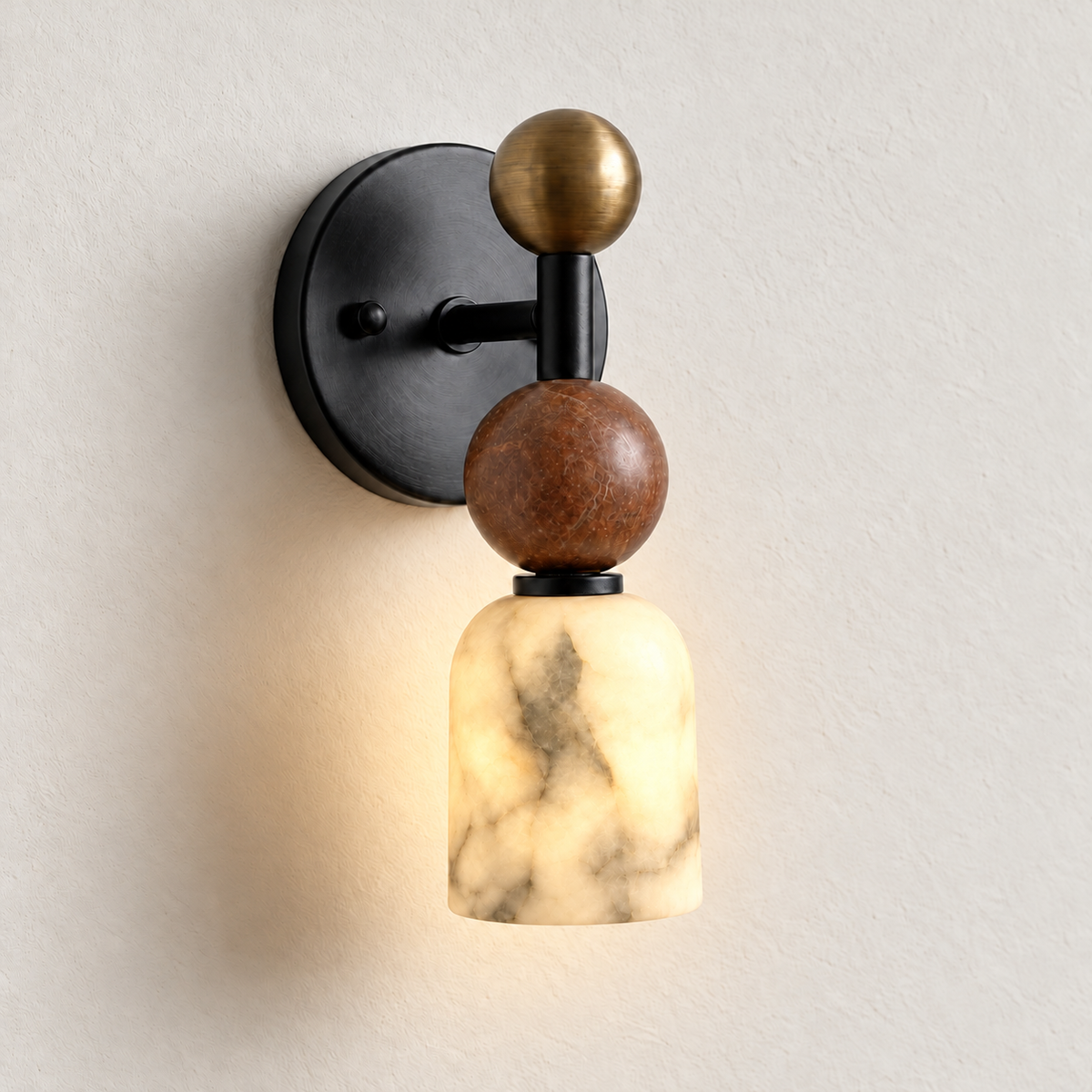 Black Totem Petite wall sconce with its alabaster cup glowing warmly, photographed at the same angle on warm ivory.