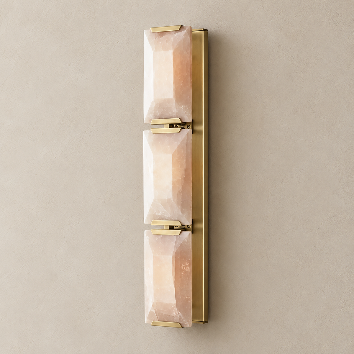 Triple calcite wall sconce with brass hardware, switched off on a beige wall.