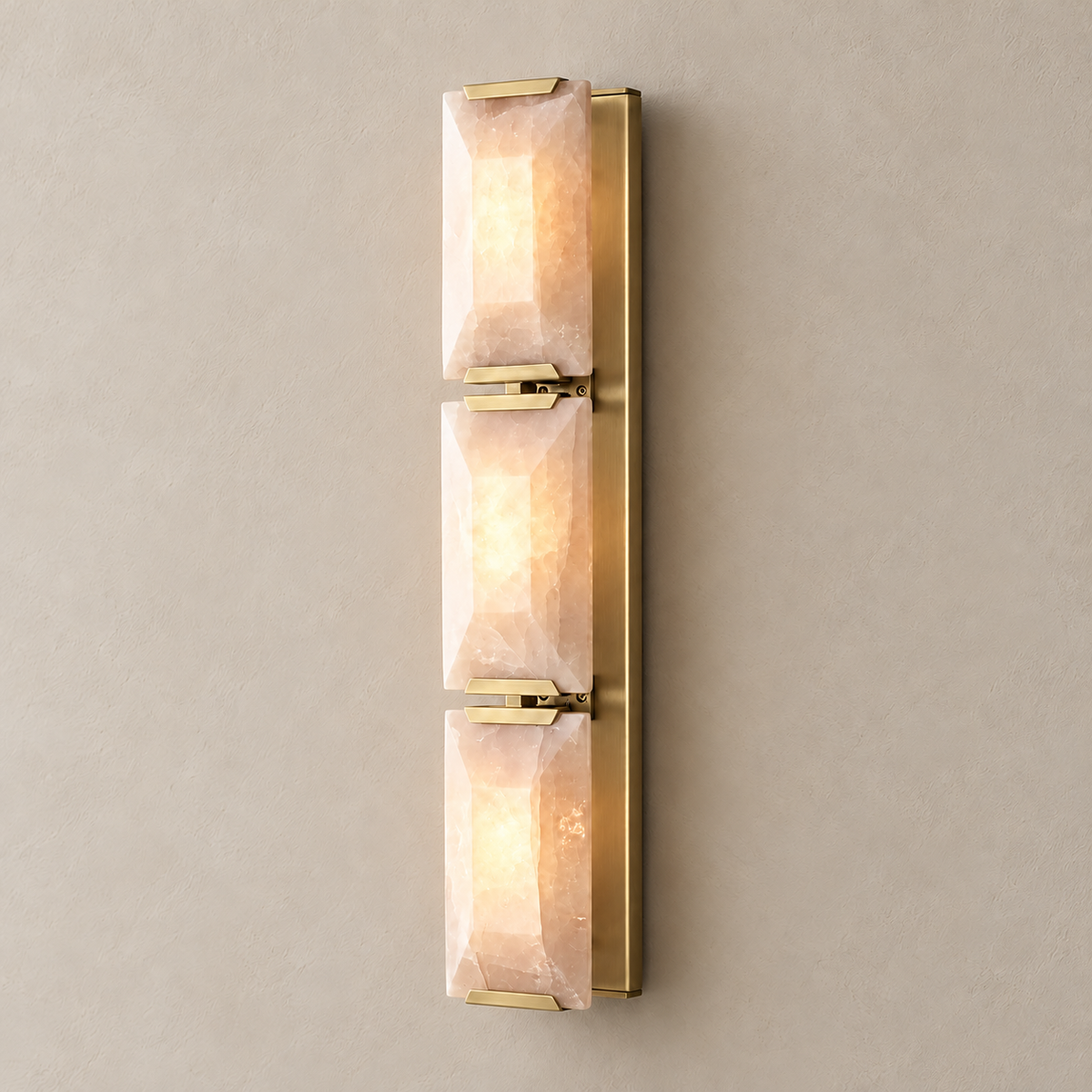 Triple calcite wall sconce with brass hardware, illuminated through the natural stone.