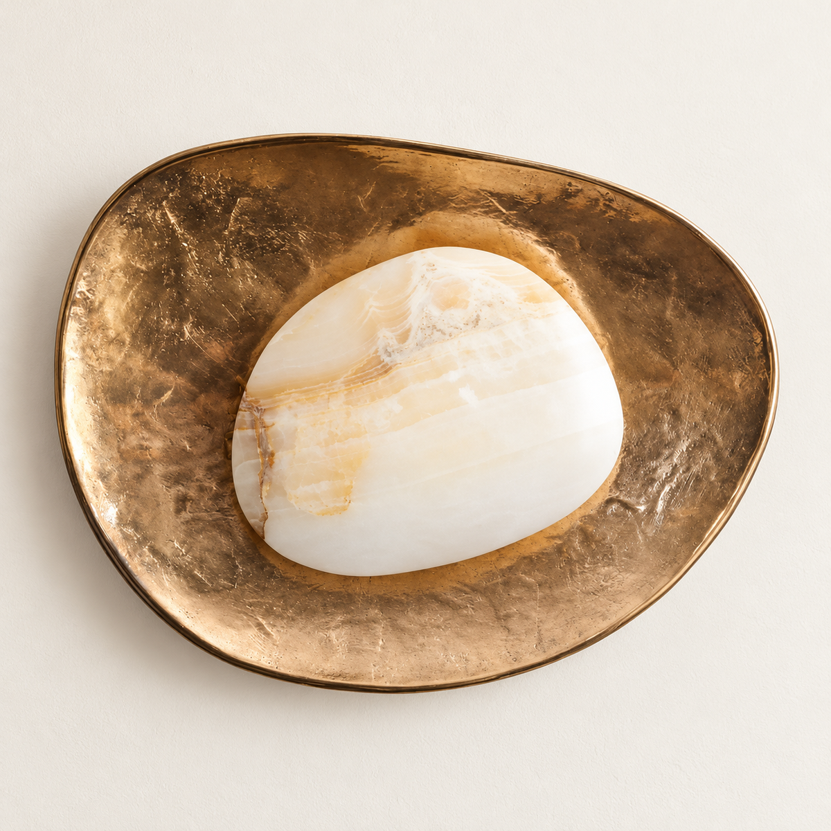 Marble and textured brass wall sconce, switched off on ivory plaster.
