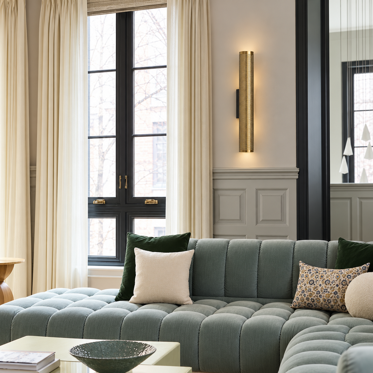 Perforated brass wall sconce above a blue-grey sofa.