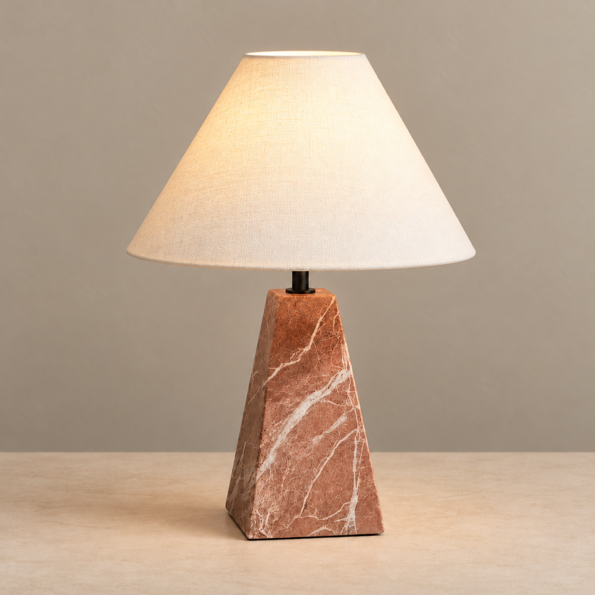 Red marble table lamp with an ivory fabric shade, illuminated on a beige background
