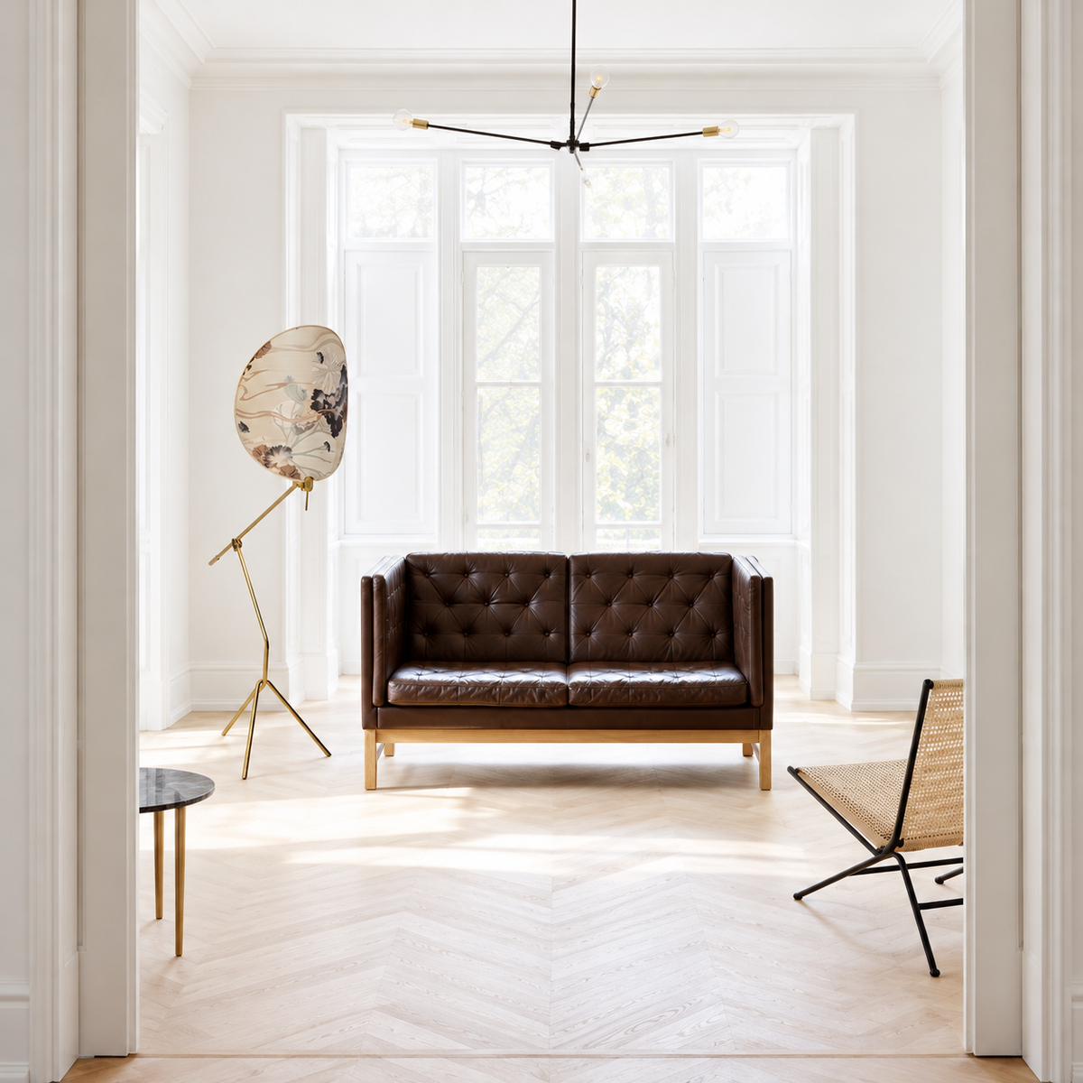 White floral floor lamp beside a brown leather settee in a bright sitting room.