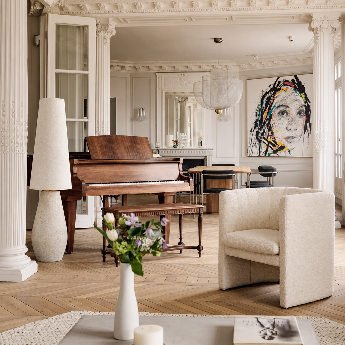 Como floor lamp beside a wooden piano in a Parisian living room with a cream armchair