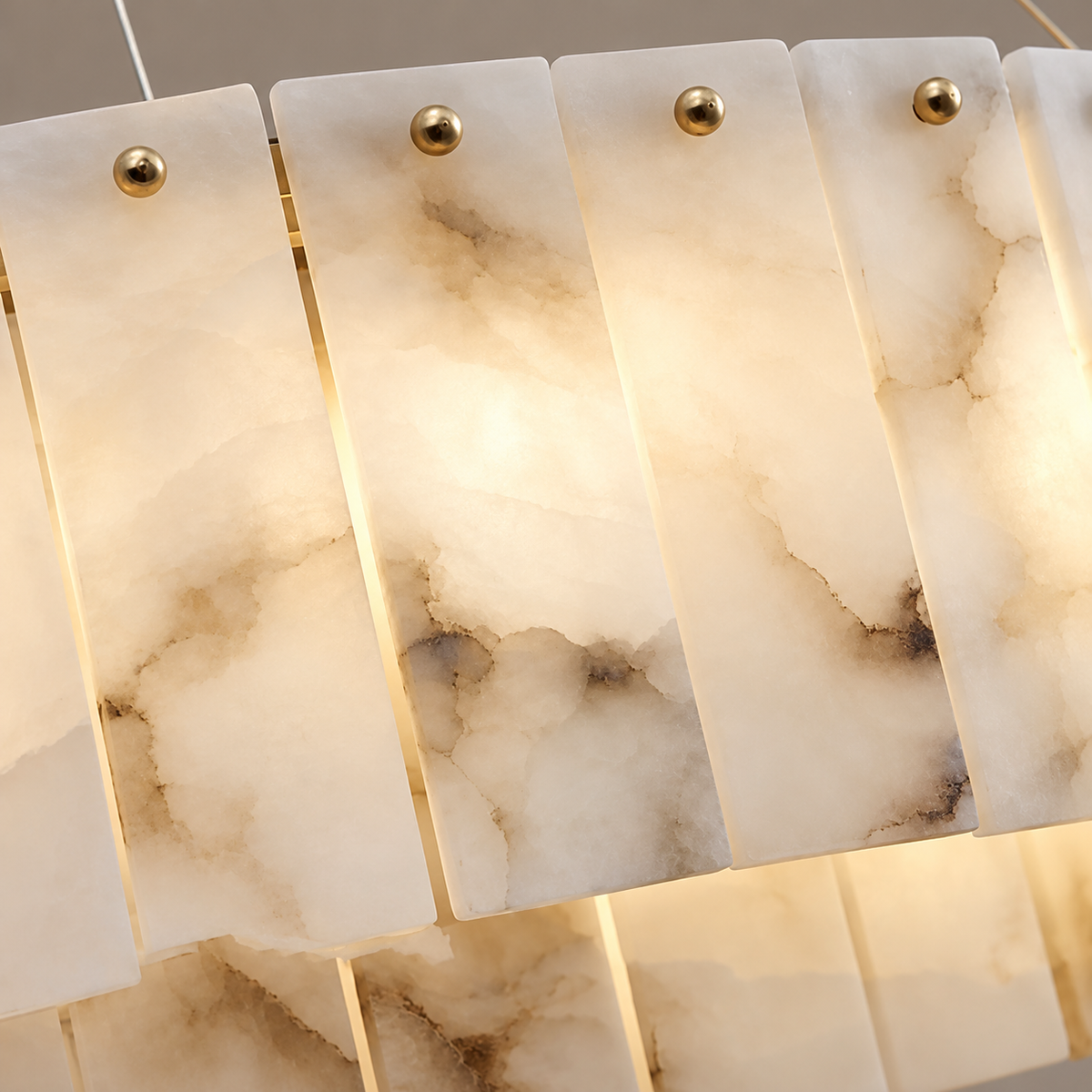 Close view of layered alabaster panels and brass fixing studs on the double-ring chandelier.