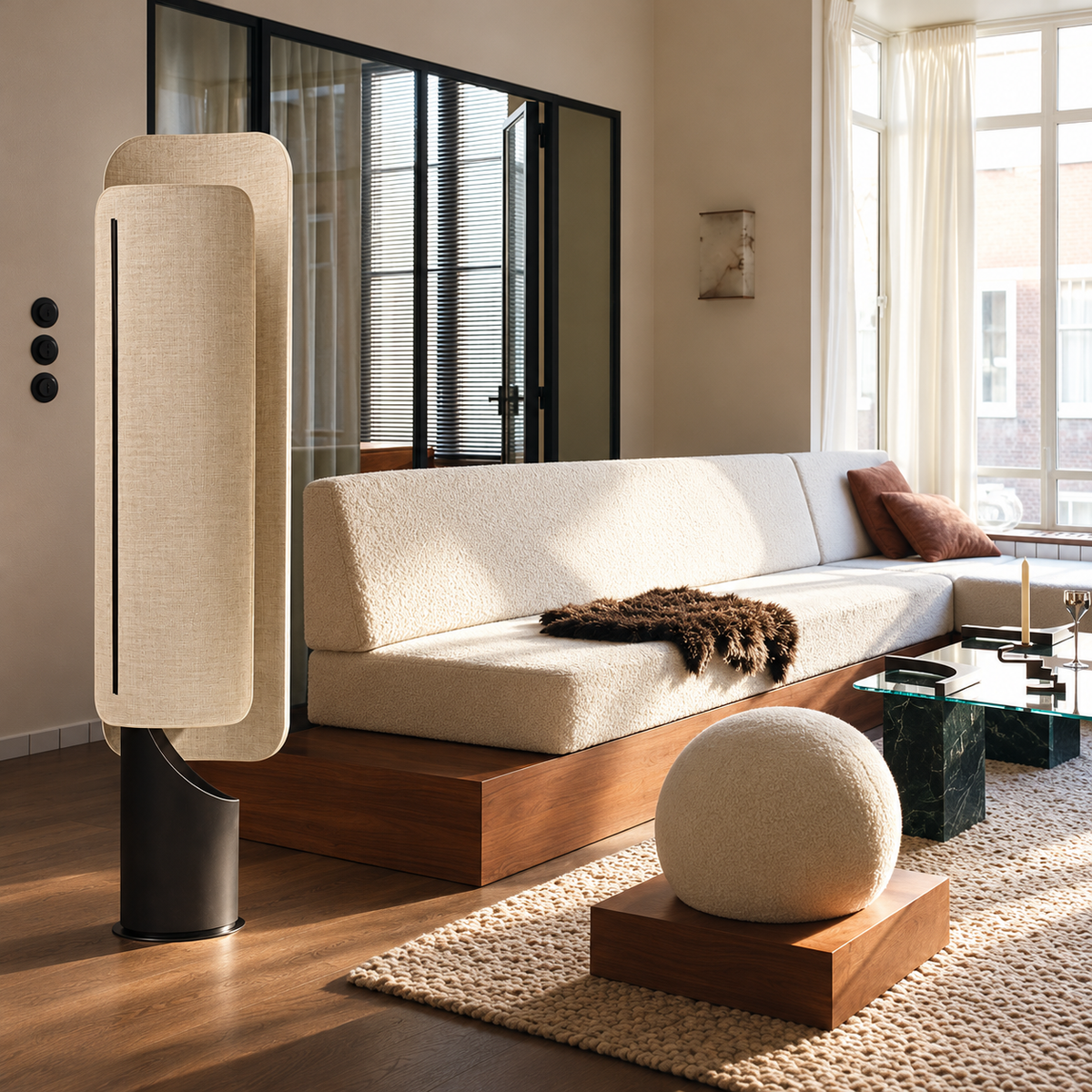 Maraki floor lamp beside a cream sofa on a wood platform in a daylight living room.