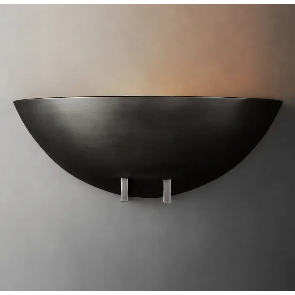 Modern black bowl wall sconce casting upward light in a living room