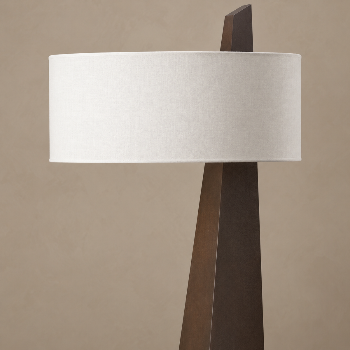Close view of Monolith’s white linen drum shade and angled wood tip projecting above it.