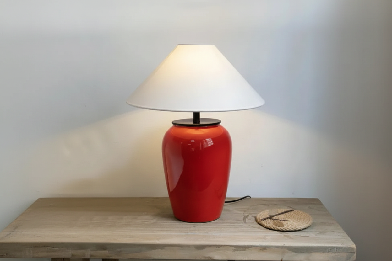 Red ceramic lamp beside a bed