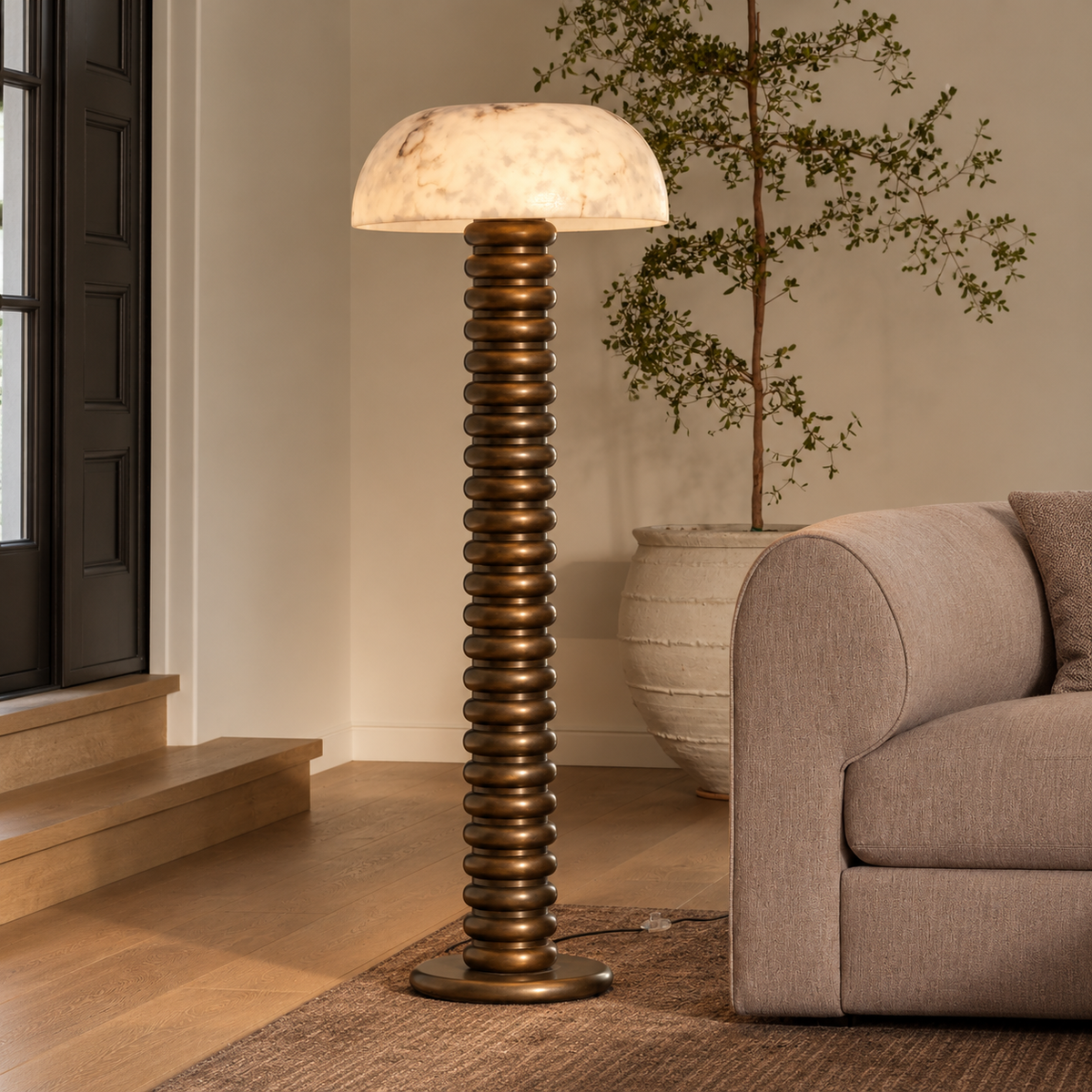 Illuminated Roma alabaster floor lamp on a rug beside a neutral sofa and shuttered window.