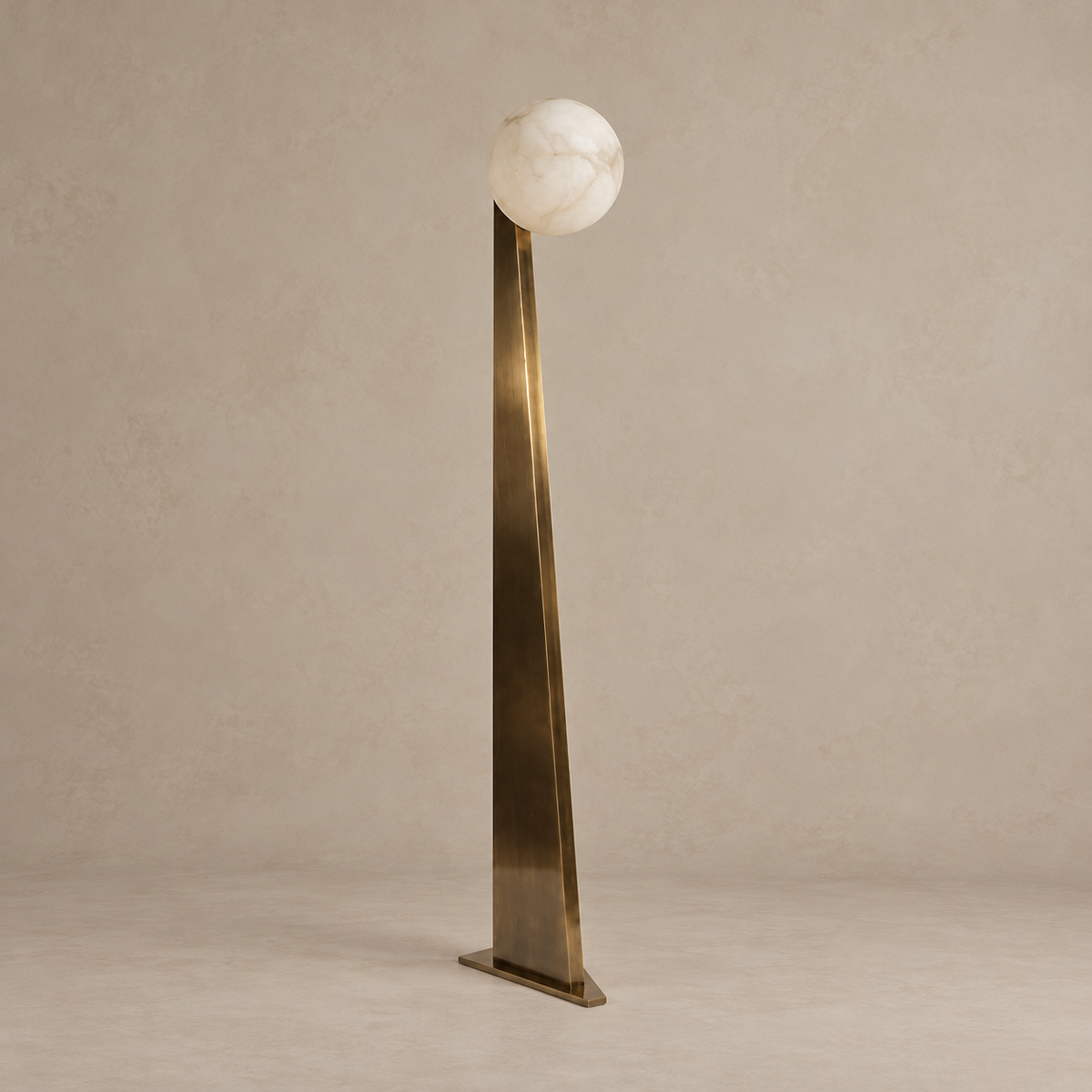 Sculptural floor lamp with a solid tapered patinated-brass support and alabaster globe, switched off.