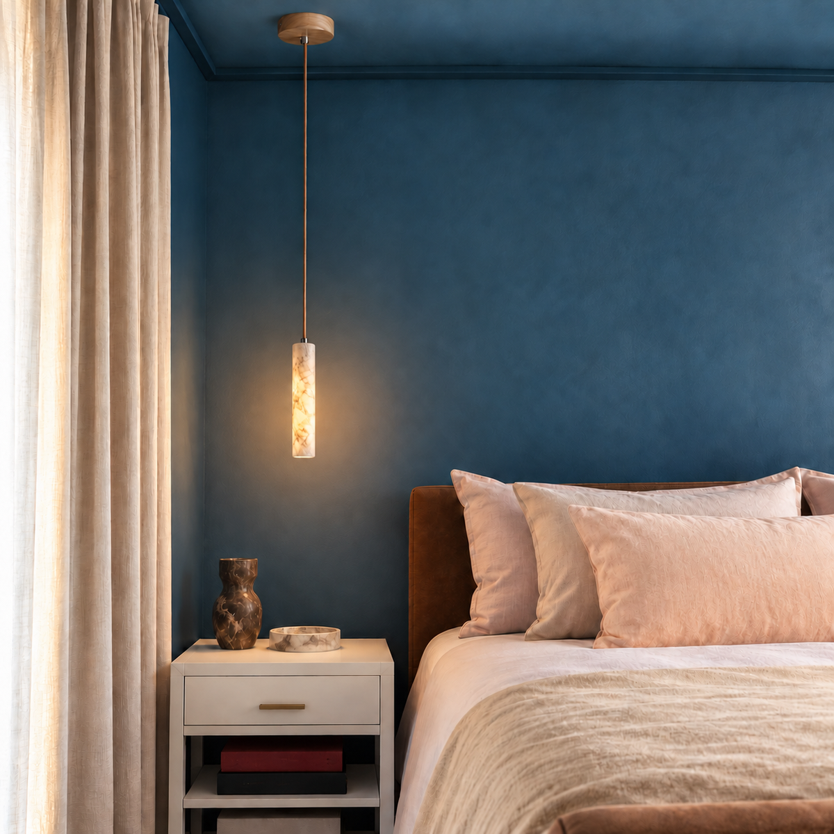Slim Stone alabaster pendant installed beside a bed in a blue bedroom with natural daylight.