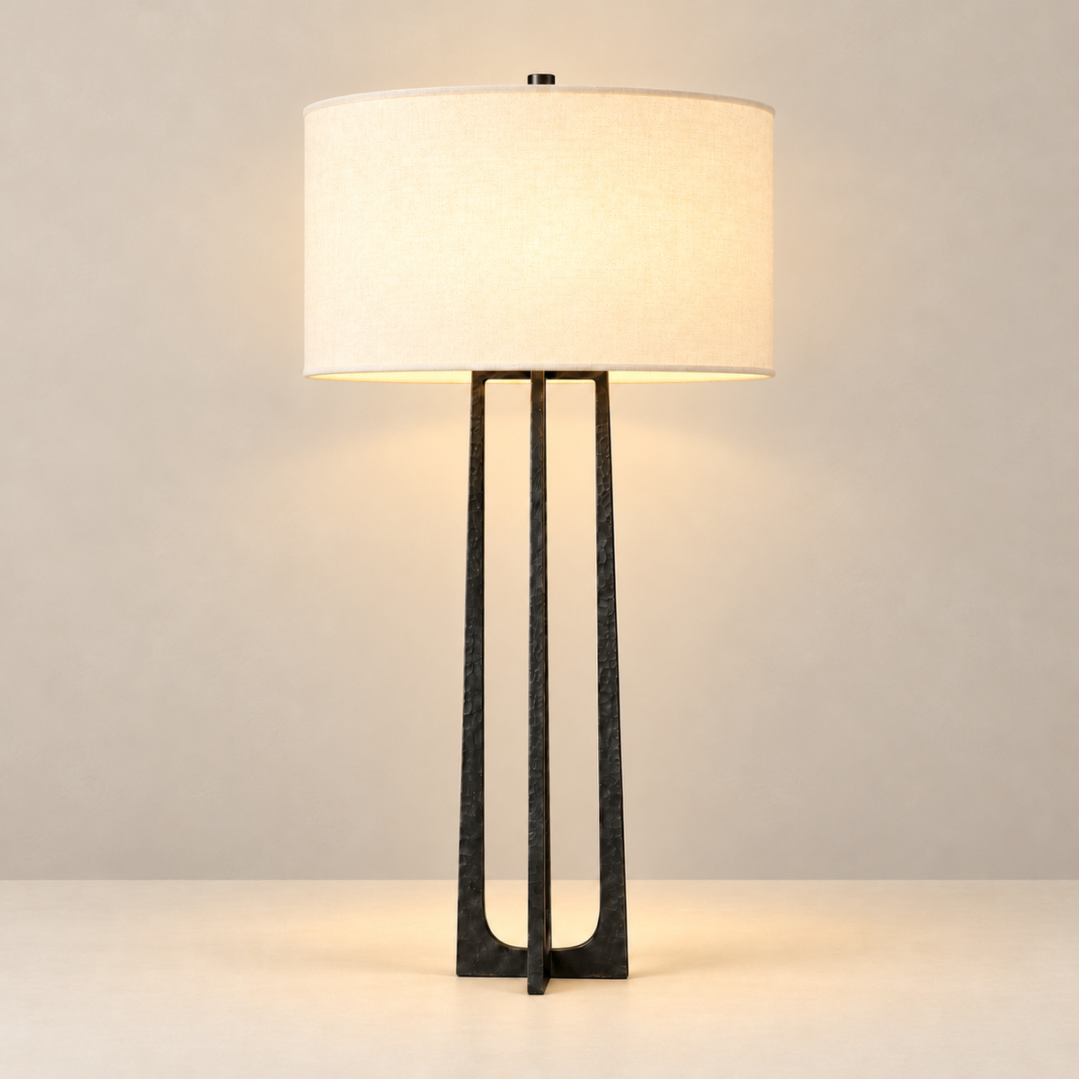 Tall Black Hammered Copper Table Lamp, illuminated, on a beige background.
