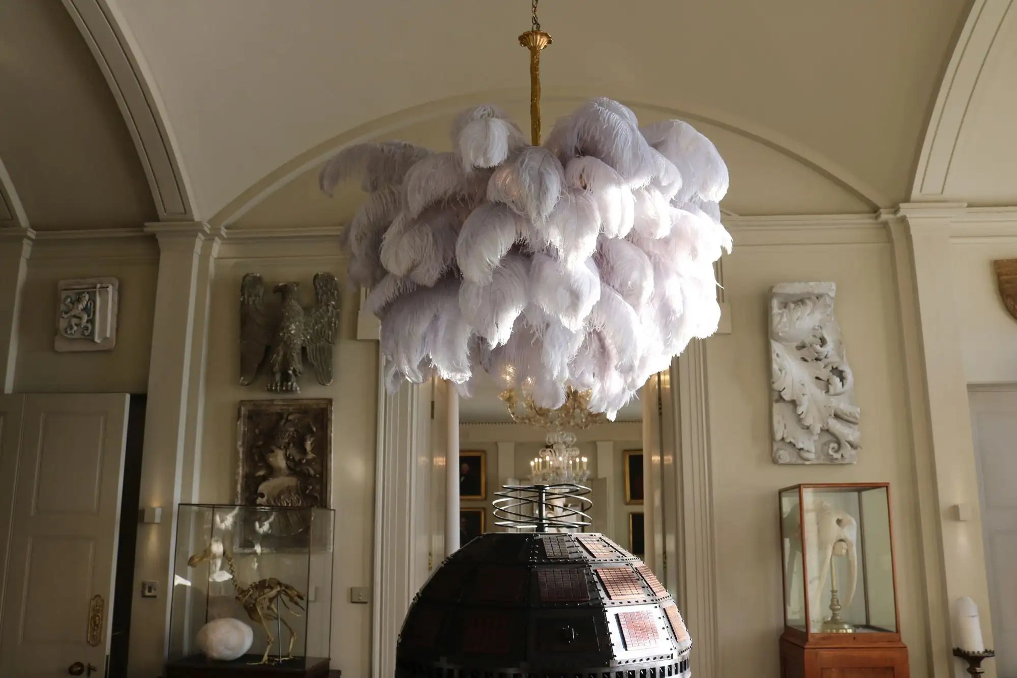 A voluminous white feather chandelier with a gold-toned central fixture.